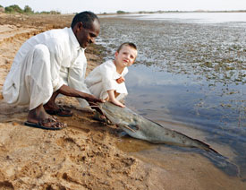 Ahmed and a young helper releasing a Vundu catfish